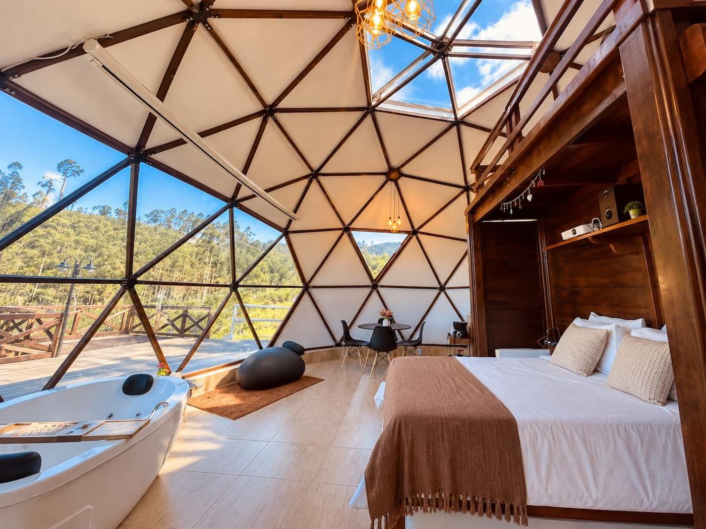 Interior do Domo com hidromassagem, cama e vista para a mata